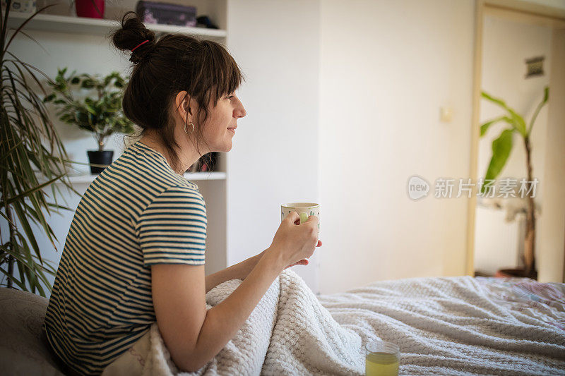 年轻女子在享受她的第一杯清晨咖啡。