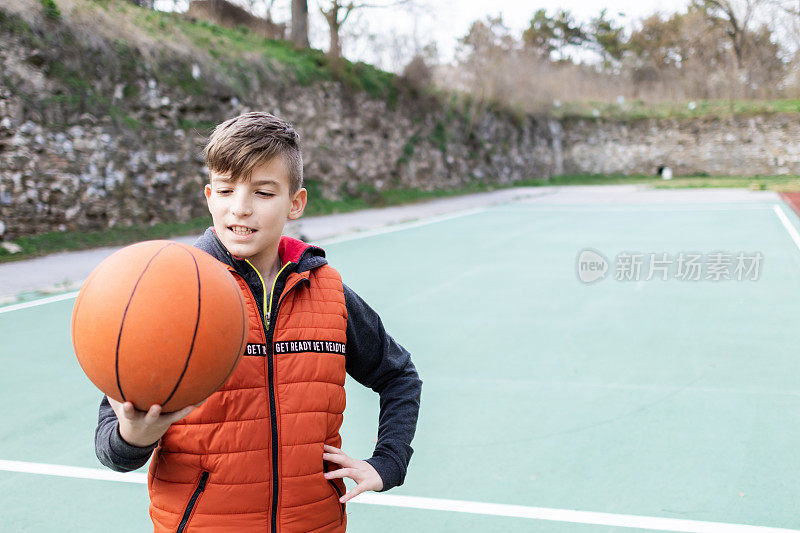 一个男孩在体育场上拿着篮球的照片。