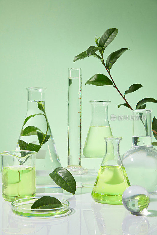 在绿色的背景下，白色的桌子上整齐地摆放着许多不同的实验工具。照片从正面拍摄，留出设计空间
