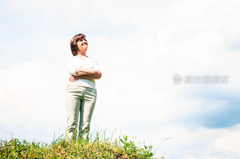 老妇人站在阴云密布的夏日天空前