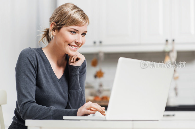 微笑的女孩工作在笔记本电脑在家里