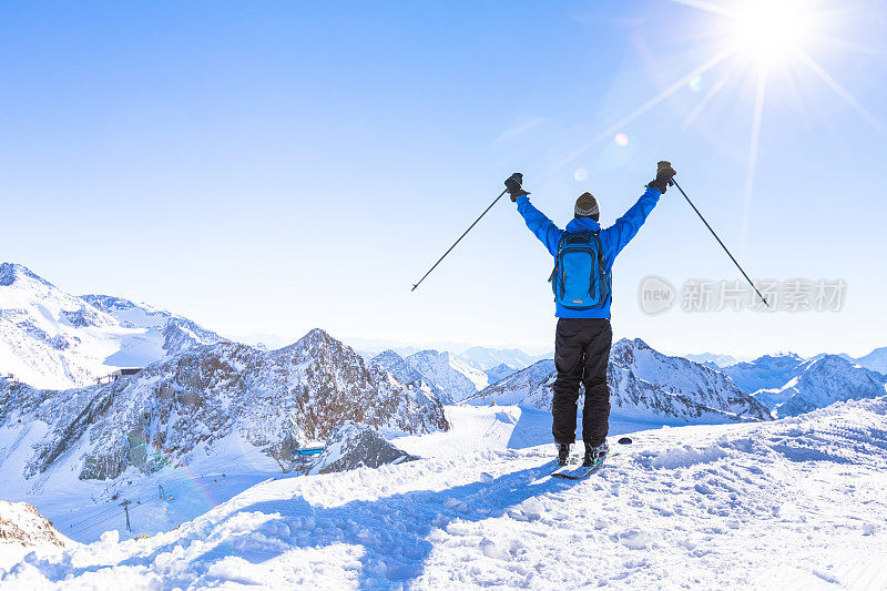 一个快乐的滑雪者举起双手的后视图
