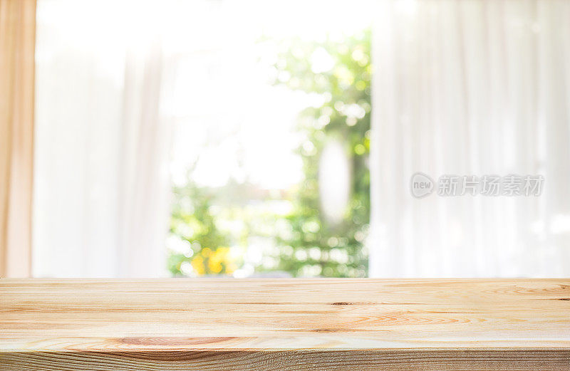 木质桌面，模糊窗帘和绿色花园。