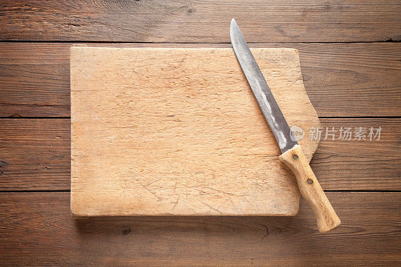 木制背景上的旧砧板和刀