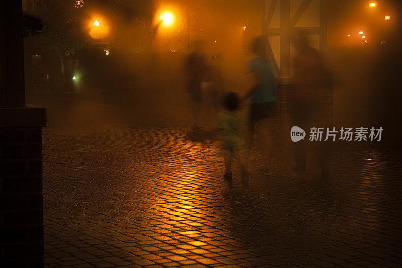 晚上有雾的砖街，行人走过。