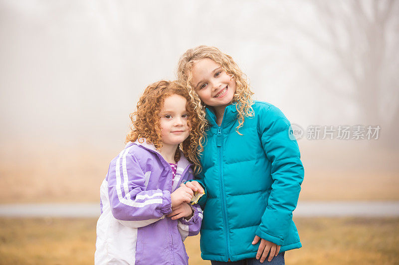 两个小女孩在雾天对着相机微笑