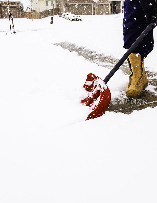 在暴风雪中从车道上铲雪的人