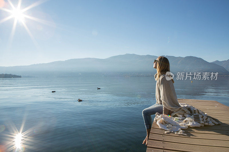 年轻女子在湖边码头上休息，看风景