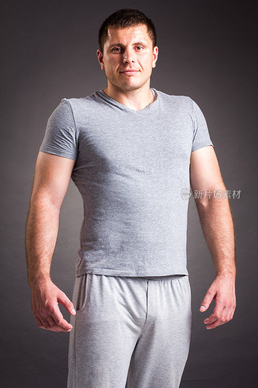 肖像强壮健康英俊的运动员健身模型摆近暗灰色墙
