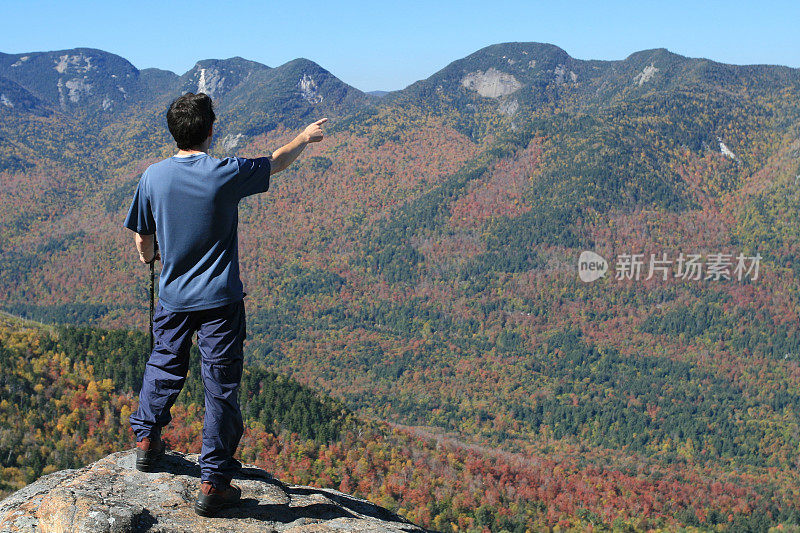 在山顶上的徒步旅行者和指向一个方向