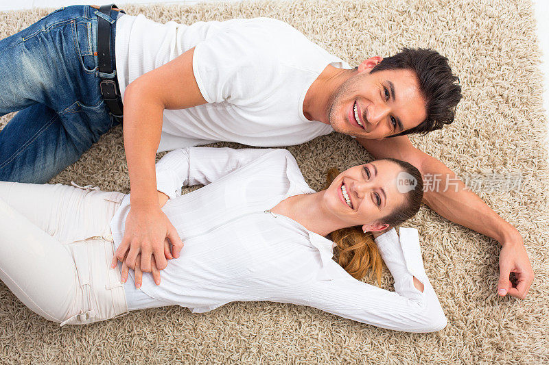 一对年轻夫妇躺在地毯上