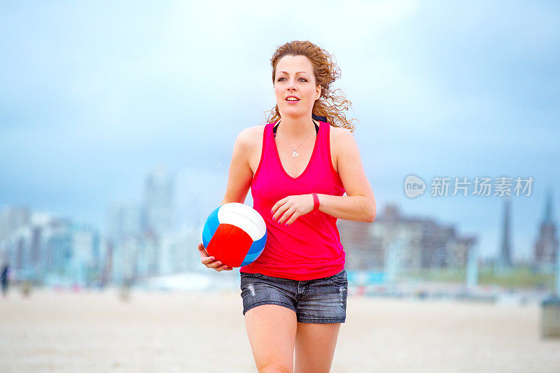 美丽的年轻女子在夏天打沙滩排球