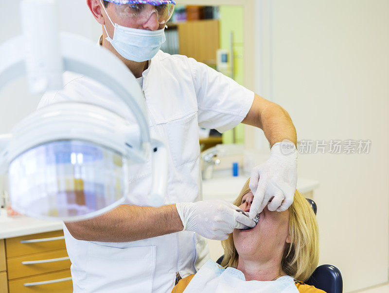 看牙医的中年妇女……医生检查模型的假牙