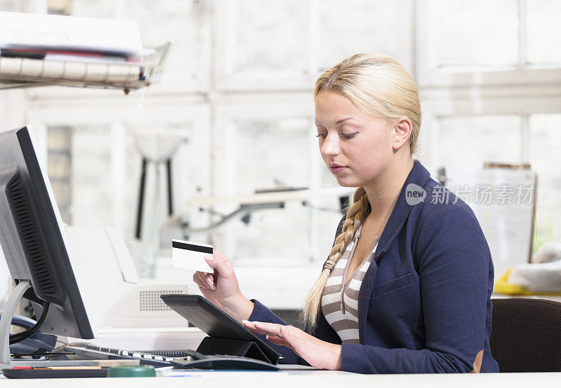 在平板电脑上打字用信用卡的商业女性