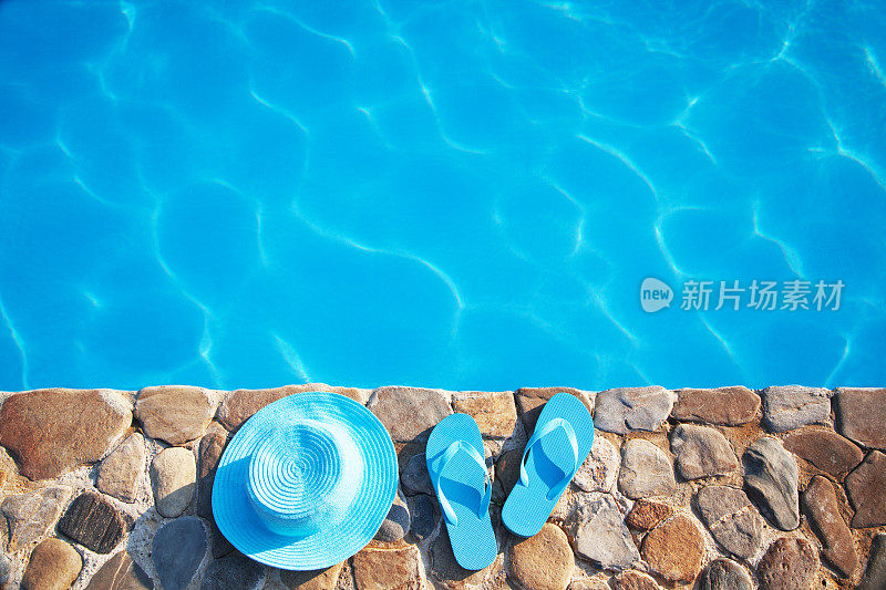 戴着蓝帽子，穿着人字拖在游泳池边