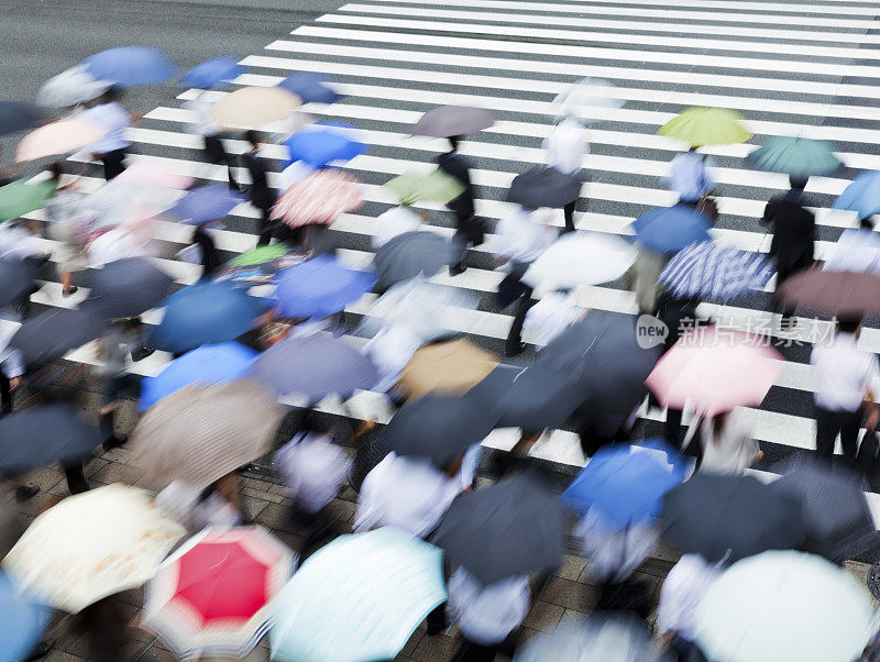 繁忙的人行横道场景在雨天与模糊运动