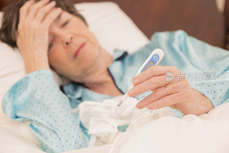 医疗保健:患流感卧床不起的妇女。温度计。