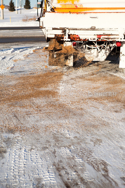 扫雪机在冬雪路上撒沙子