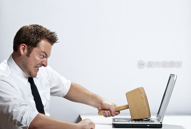 一名愤怒的男子用锤子砸笔记本电脑
