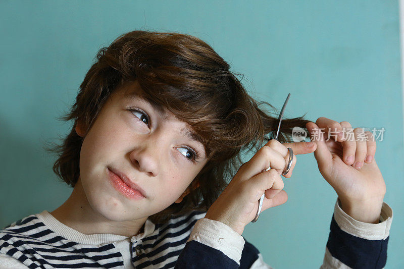 一个十几岁的男孩用剪刀剪头发