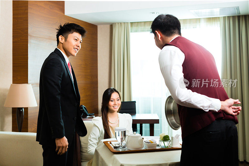 亚洲华人客房服务员在酒店套房提供食物