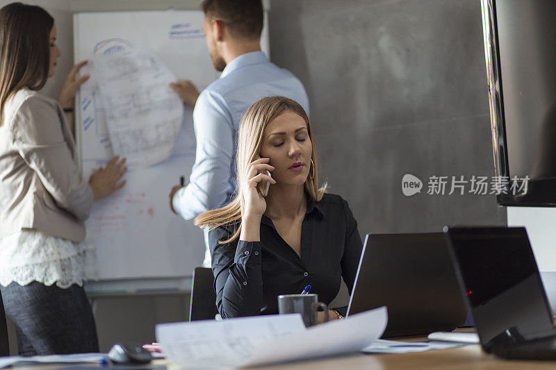 年轻女商人在办公室使用智能手机