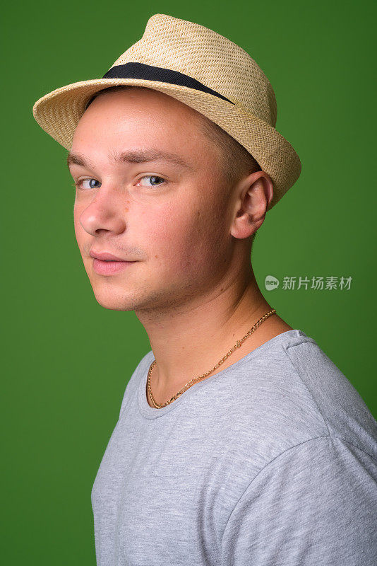 摄影棚拍摄的年轻英俊的游客男子穿着灰色衬衫，以绿色为背景