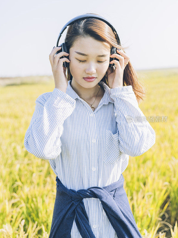 年轻女孩戴着耳机在野外
