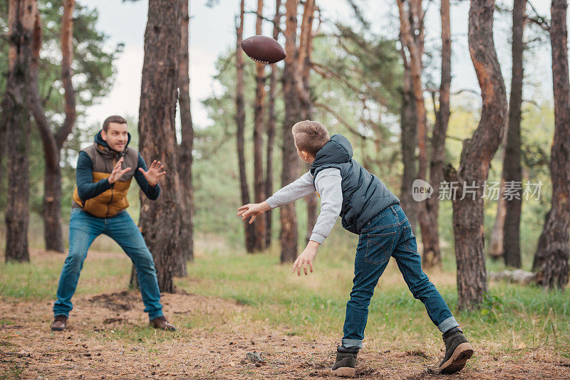 爸爸和儿子在森林里玩球