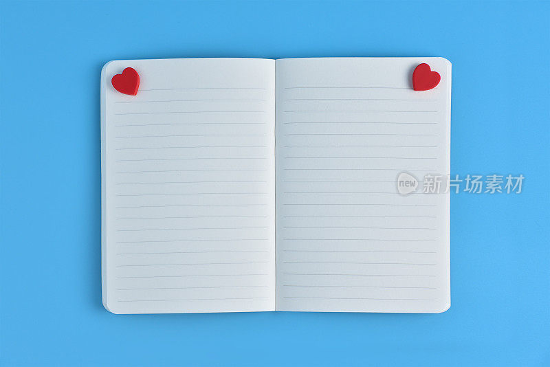 两颗红心和打开的笔记本空白页。