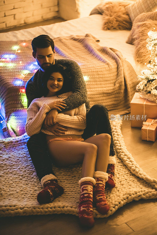 热情洋溢的情侣们穿着毛衣在家里过年。