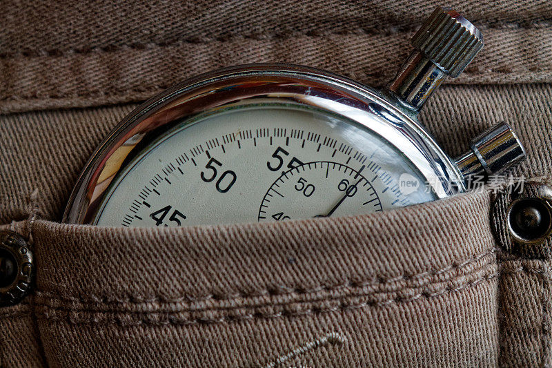 古董秒表，在破旧的米色牛仔裤口袋里，测量时间的价值，旧式时钟箭分，秒精确计时记录