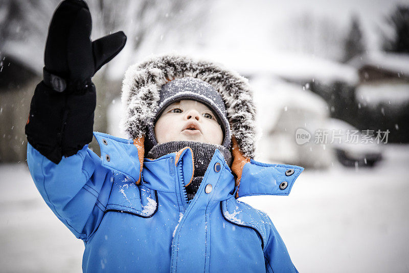 穿着蓝色冬装的小男孩和雪玩