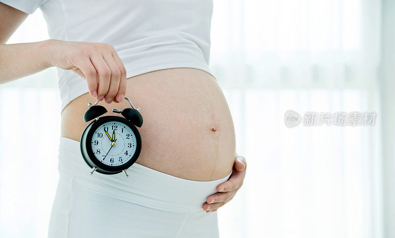 一个孕妇把闹钟放在肚子上