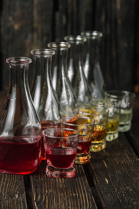 深色木质背景的玻璃杯和醒酒器里的各式各样的酒