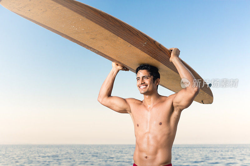 西班牙冲浪手微笑着把冲浪板举过头顶