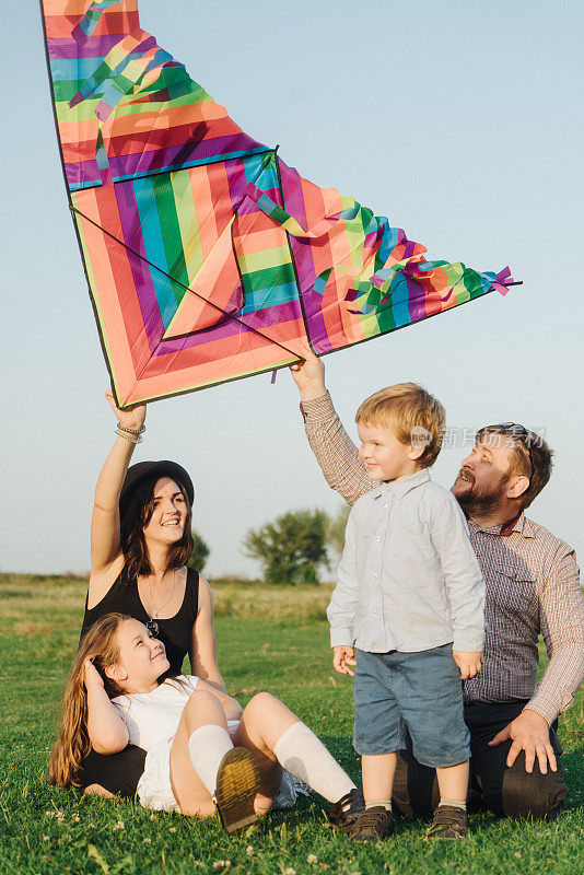 一家人带着两个孩子在草地上玩风筝