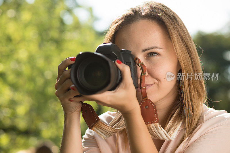 一名女摄影师拿着相机靠近她的脸拍照