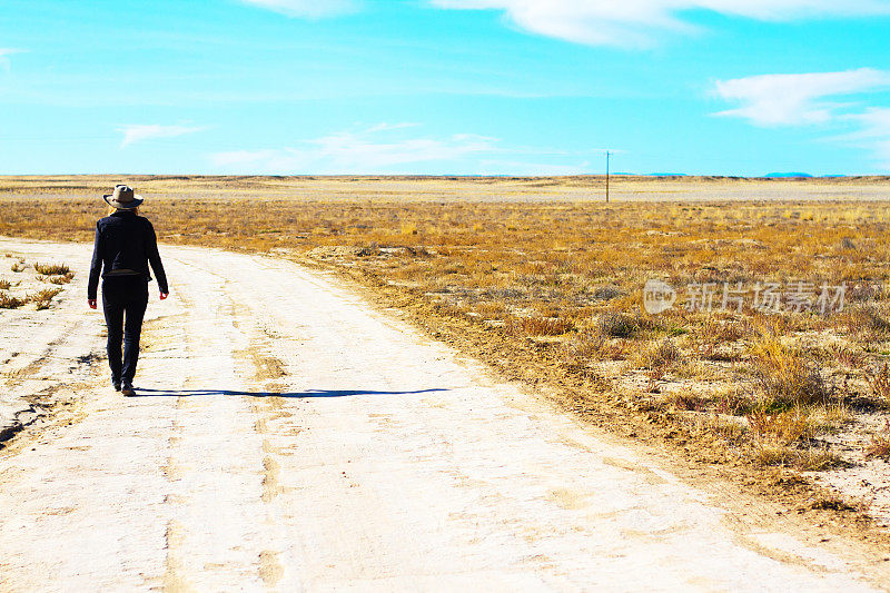 在草原荒野的泥土路上独自行走的女人