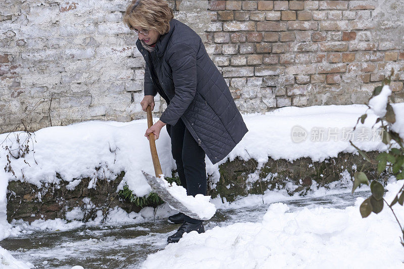 老妇人在她的后院清理积雪