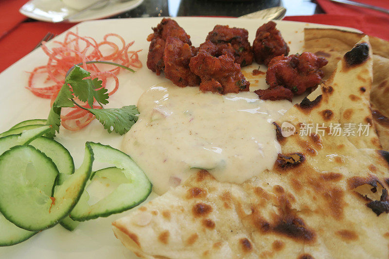 印度德里，印度男人在印度餐馆用餐，食物盛在盘子里，辣炸鸡肉炸丸子，大蒜馕饼，烤饼，肉配印度螺旋黄瓜和胡萝卜沙拉