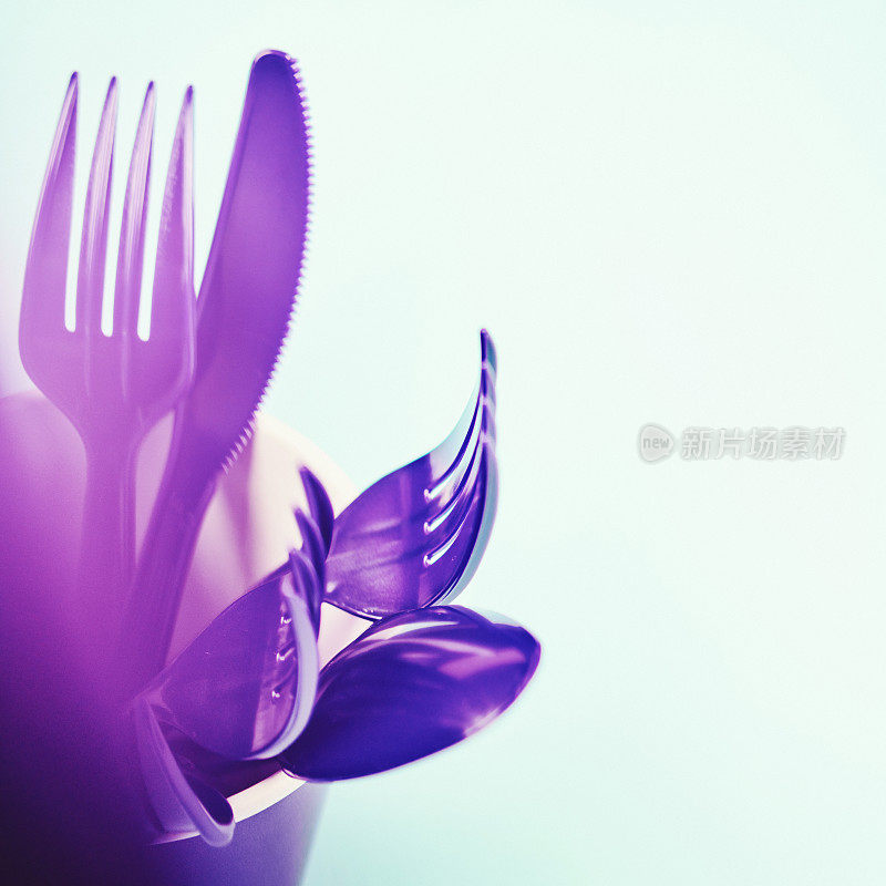 一次性杯子，装满紫色的刀叉和勺子