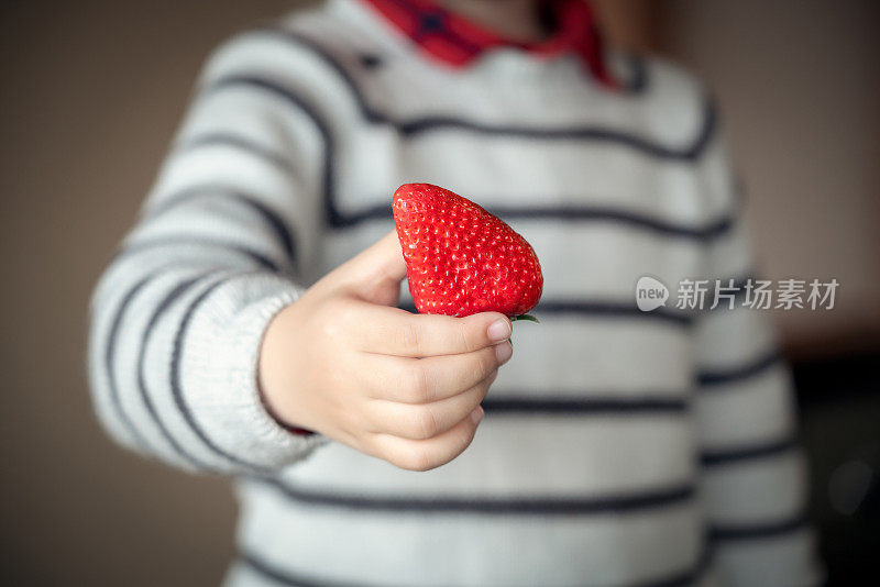 小男孩拿着草莓分享