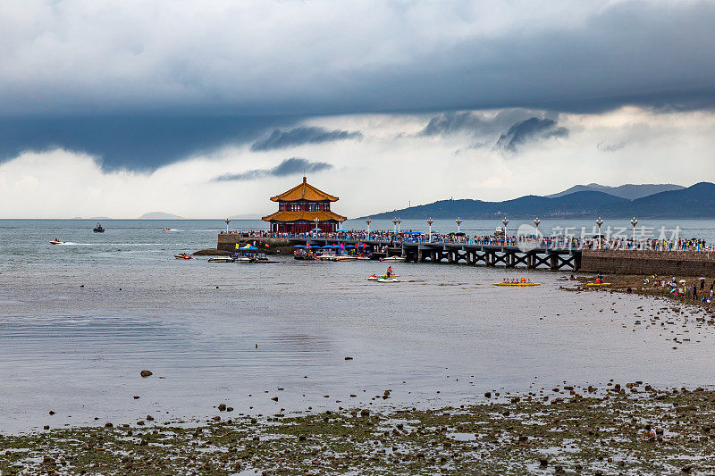 湛桥码头在暴风雨的天空下，青岛，中国，山东。栈桥是青岛啤酒酒瓶上展示的著名展馆