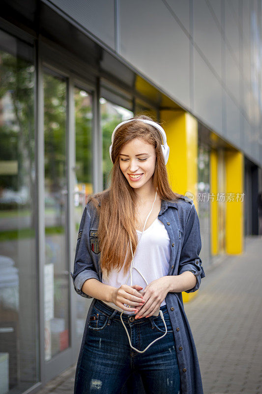 在城市街道上听音乐的美丽女人