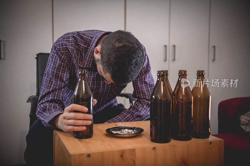 年轻悲伤的醉酒男子喝啤酒和酒精感到浪费，孤独和绝望的痛苦和情绪压力。人与酗酒、上瘾和男人抑郁的概念。