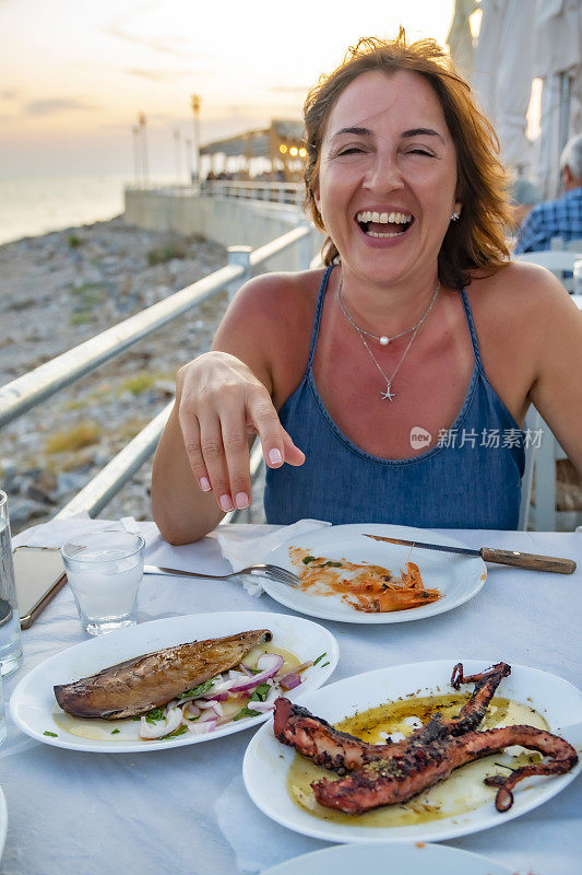 希腊女人享受美味的希腊食物和茴香酒。