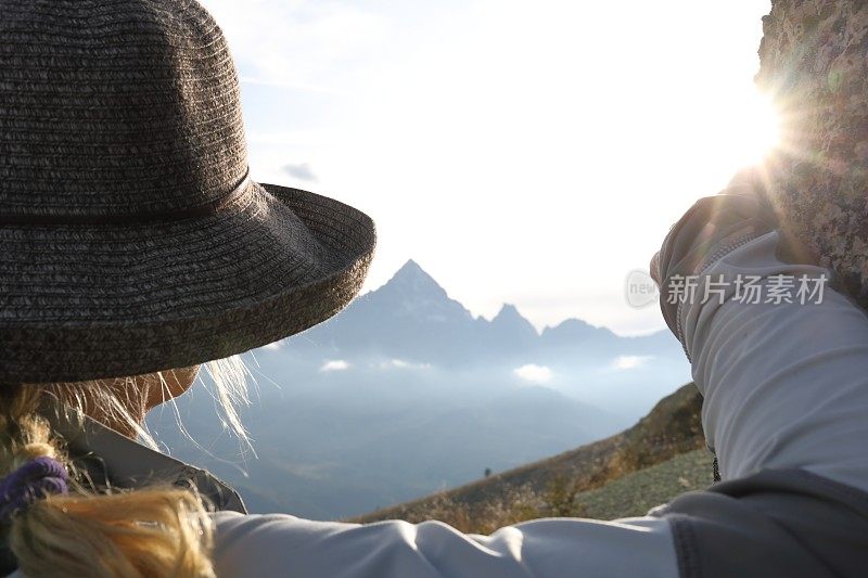 日出时分，女徒步旅行者在高山休息