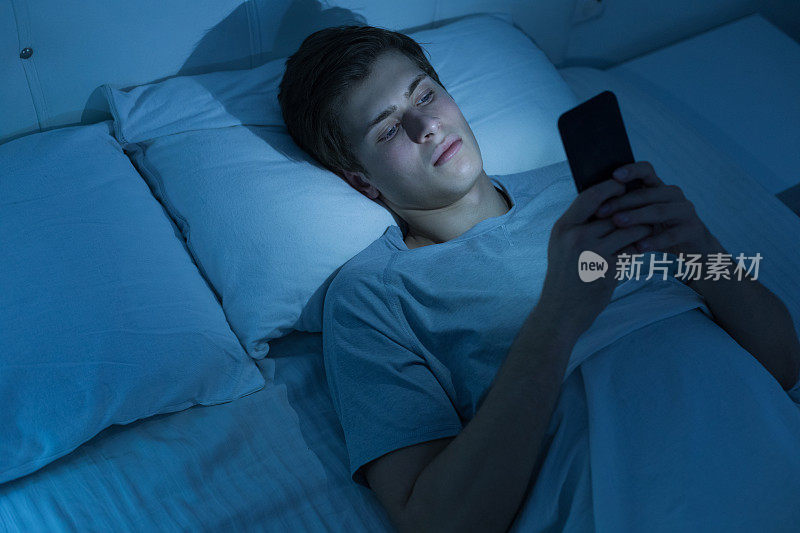 年轻人晚上在床上玩手机