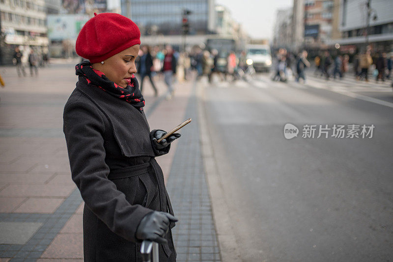 漂亮的肤色女人使用手机应用程序得到一个出租车